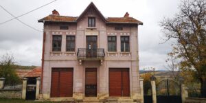 Two-storey representative house with symmetrical facade, central balcony, wrought iron railing, decorative consoles, mascarons and vegetal motifs.